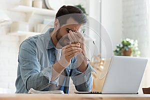 Tired young man feel eyestrain holding glasses fatigued from computer