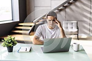 Tired young man feel pain eyestrain holding glasses rubbing dry irritated eyes fatigued from computer work, stressed man suffer