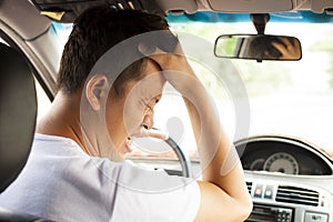 Tired young man have a headache while driving car.