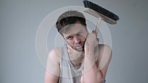 Tired young man with mop on white background