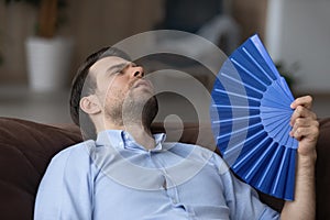 Tired young man wave with hand fan suffer from heatstroke photo