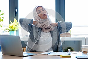Tired young muslim business woman wearing hijab with neck pain at the office