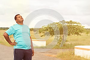 Tired young obese man holiding his back while jogging - Concept of fat man fitness and unhealthy lifestyle.