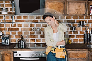 tired young repairwoman with pain in neck leaning back