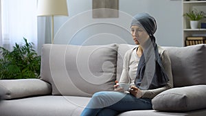 Tired young woman with cancer sitting at home and drinking tea, remission