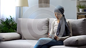 Tired young woman with cancer sitting at home and drinking tea, remission