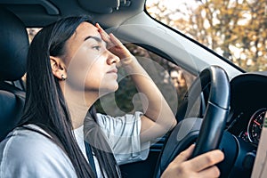 Tired young woman car driver suffering from headache migraine driving vehicle.