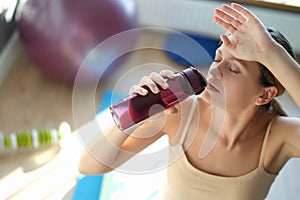 Tired young woman drinks water after training closeup