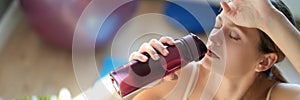 Tired young woman drinks water after training closeup