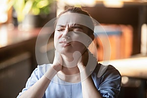 Tired young woman feel neck pain rubbing stiff neck