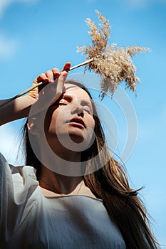 Tired young woman holding fluffs at her forehead, low angle