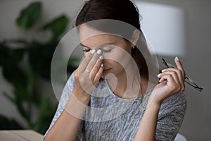 Tired young woman massage eyes suffering from headache