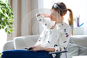 Tired young woman with neck pain holding her mobile phone at the office