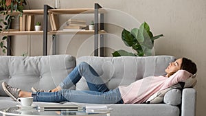 Tired young woman relax at home sleeping on cozy couch