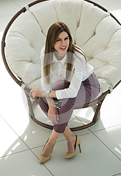 Tired young woman sitting in comfortable round chair