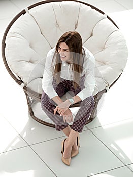 Tired young woman sitting in comfortable round chair