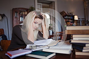 Tired young woman student of the University. Preparing exam and learning lessons in public library.