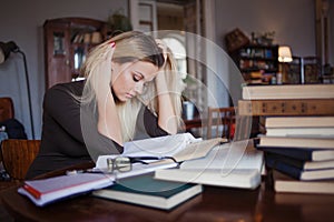 Tired young woman student of the University. Preparing exam and learning lessons in public library.