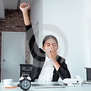 Tired young woman trying not to fall asleep while working