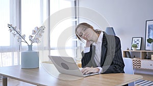 Unavený mladá žena pracovné na prenosný počítač v kancelária 