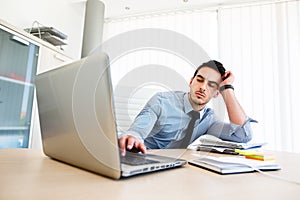 Tiresome businessman works on laptop