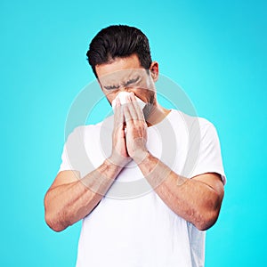 Tissue, nose and man in studio for sick allergy, cold and influenza on blue background. Asian male model sneeze wit