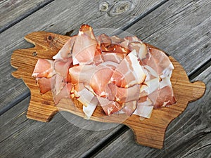 Tissue thin slices Tyrolean Speak, Smoked bacon on wooden cutting board