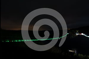 Titan RT suspension rope bridge illuminated in green at night over the Rappbodetal