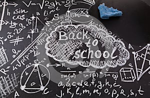 Title Back to school, formulas written by white chalk on the black school chalkboard and blue rag for erasing