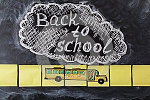 Title Back to school written by chalk on the chalkboard and the school bus drawn on pieces of paper