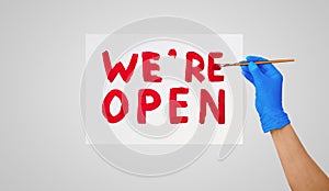 Title lettering in colors. Hand in a blue glove with a brush. We are open. We`re open. Red letters