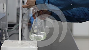 Titration reaction by shaking colorless liquid in conical flask under a burette