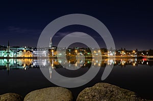 Night Reykjavik in the reflection of the Tjornin pond, Reykjavik
