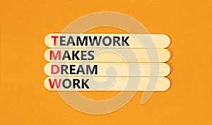 TMDW Teamwork makes dream work symbol. Concept words TMDW Teamwork makes dream work on wooden stick on beautiful orange background