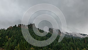 Tmelapse of rolling fog mist and low clouds over evergreen trees one early morning 4k