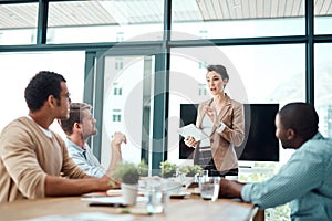 To answer your question...a young businesswoman giving a presentation to her colleagues in an office.