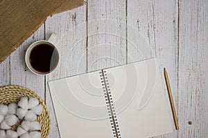 To do list concept with black coffee, notebook and cotton flowers over the wooden table.