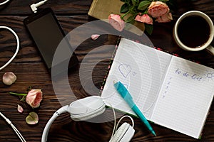 To do list conceptual. Smartphone, headphones, coffee cup and notebook on a wooden table. Top view flat lay background