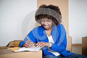 To Do List. Happy Young Black Woman Writing Checklist While Moving Home