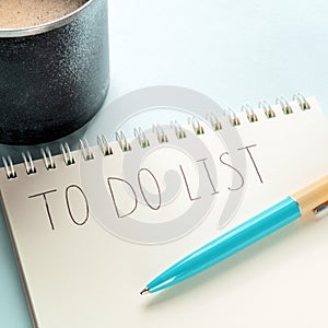 To do list, square shpt. A paper notepad with coffee and a turquoise blue pen