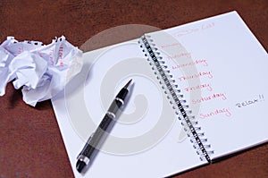 To-do list for a week. Open notebook with black cover on brown background photo