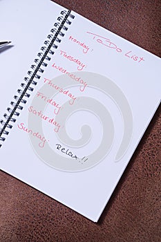 To-do list for a week. Open notebook with black cover on brown background photo