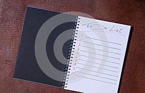 To-do list for a week. Open notebook with black cover on brown background photo