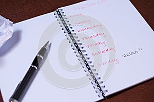 To-do list for a week. Open notebook with black cover on brown background photo
