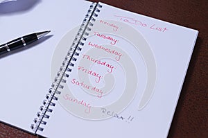 To-do list for a week. Open notebook with black cover on brown background photo