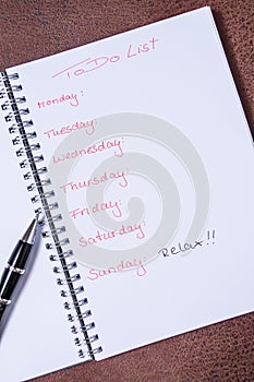 To-do list for a week. Open notebook with black cover on brown background photo