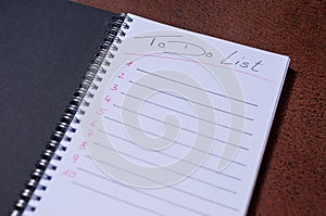 To-do list for a week. Open notebook with black cover on brown background photo