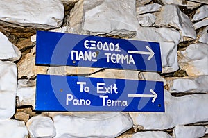 To Exit Pano Terma Funny Blue Signs Attached on the Stone Wall in Syros Island, Greece. Exit is All the Way Up on the Right. photo