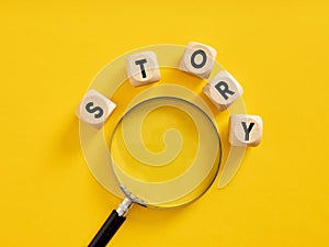 To find a story or to search for a story idea. Analyzing the story. Storytelling. The word story on wooden cubes with a magnifier
