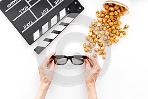 To go to the cinema. Clapperboard, glasses and popcorn on white background top view